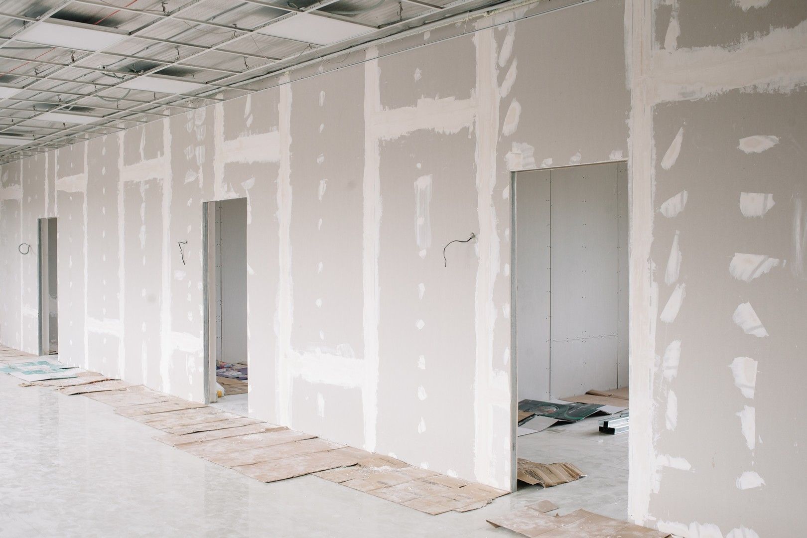 Un lungo corridoio con pareti e porte in cartongesso in un edificio in costruzione.