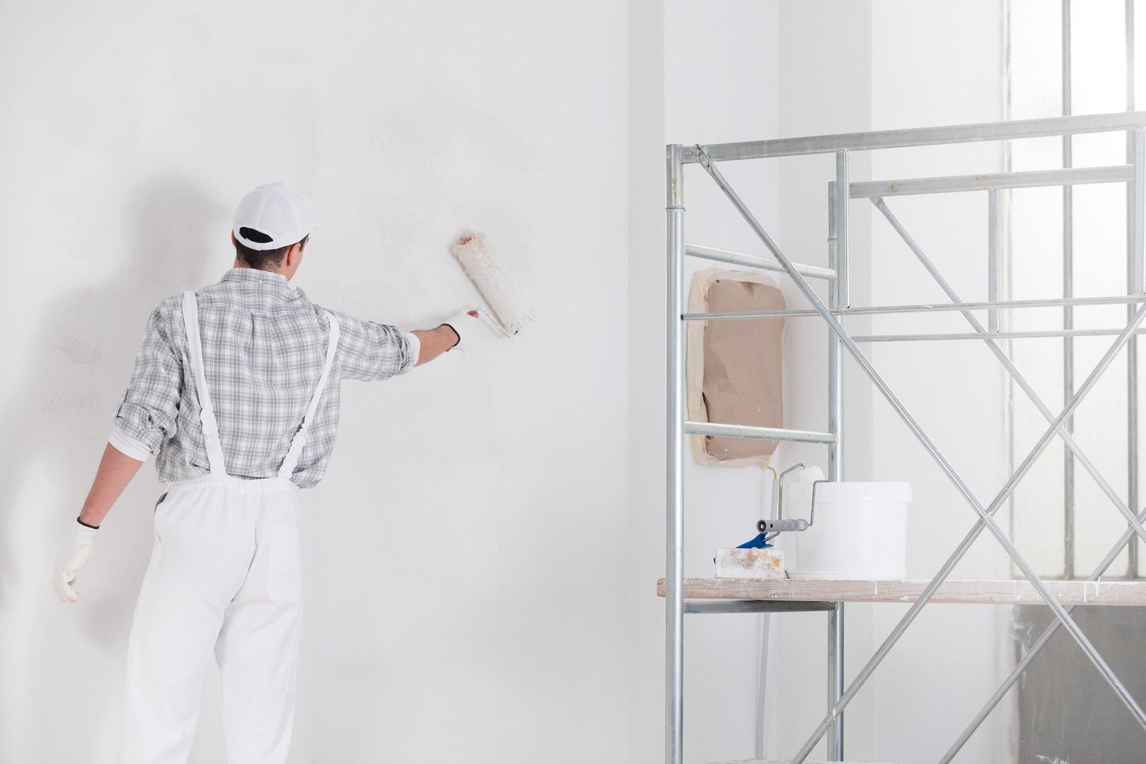 Un uomo sta dipingendo un muro con un rullo di vernice.