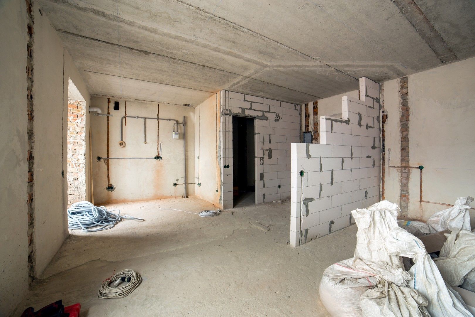 Una stanza vuota con pareti di mattoni bianchi e un soffitto in un edificio in costruzione.