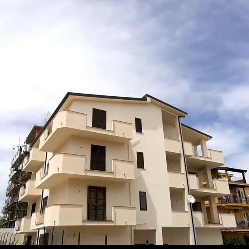 Un grande edificio bianco con balconi e un cielo azzurro sullo sfondo