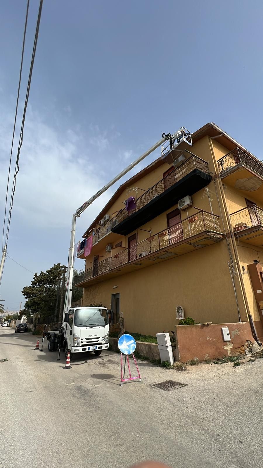 Davanti a un grande edificio è parcheggiato un camion bianco.