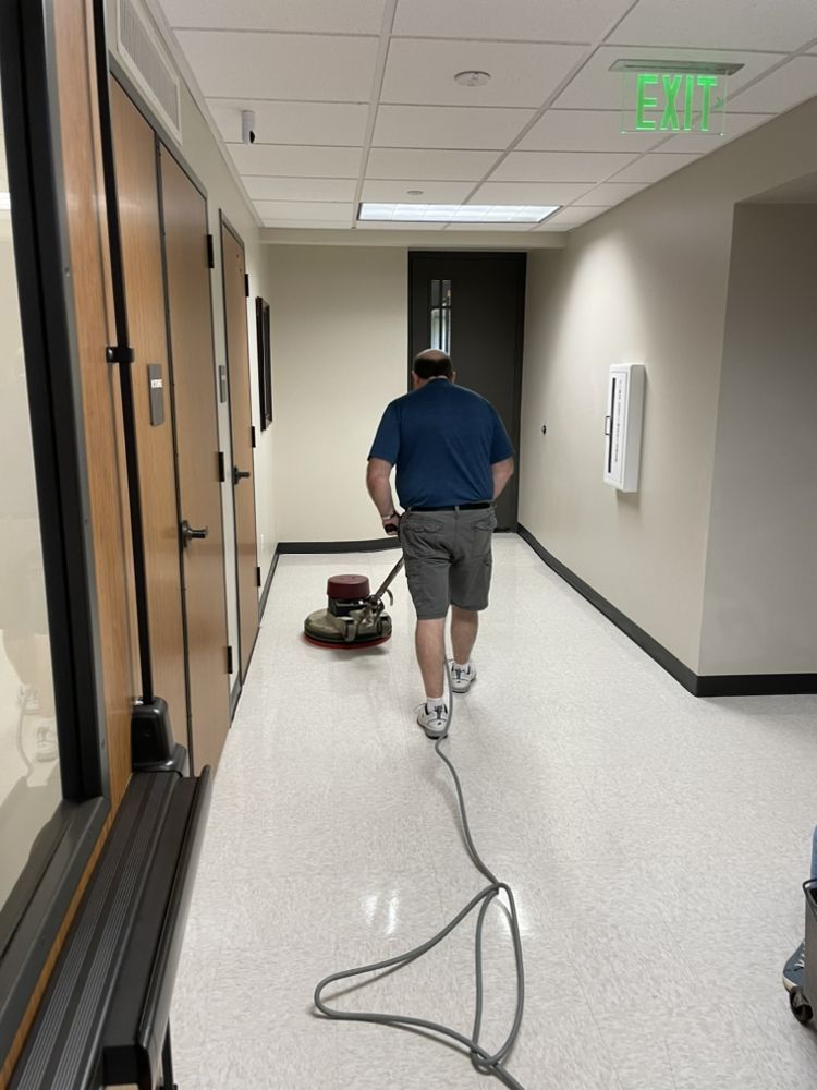 A man is cleaning the floor of a hallway with a machine.