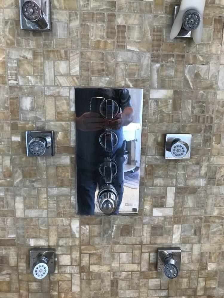 Metal light switch panel on a stone-tiled wall with six surrounding switches and outlets