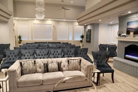 A quiet, elegantly furnished funeral home viewing room with tufted blue chairs, a cream sofa, and a fireplace.
