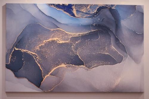 Abstract canvas art featuring flowing layers of dark blue and gray with shimmering gold veins and speckled textures.