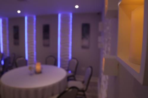 A dining area with a round table, chairs, and wall accents illuminated by vertical blue lights in a dimly lit room.