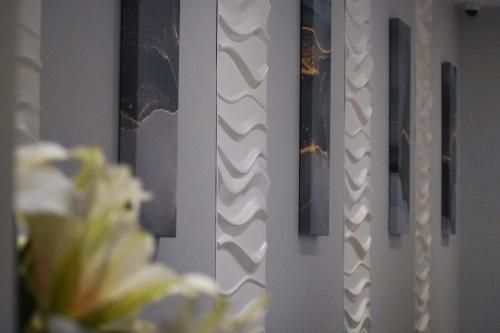 Wall art featuring vertical, dark abstract panels alternating with white, textured wave patterns in a modern space.
