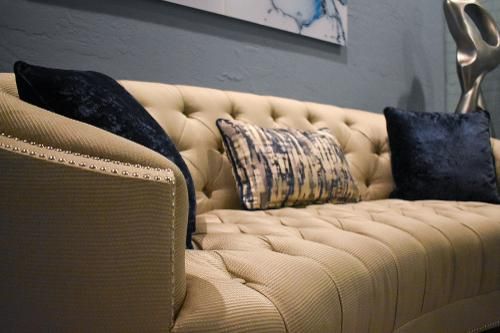 A tufted, beige sofa with navy blue and patterned throw pillows in a modern living space.