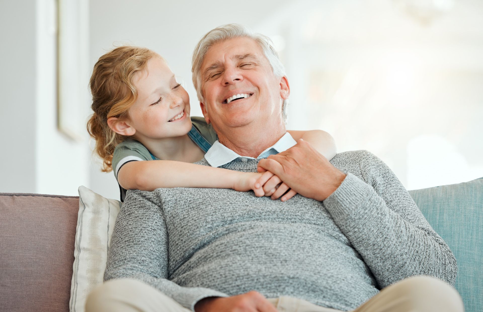 An elderly couple hugging each other on a rooftop at sunset.