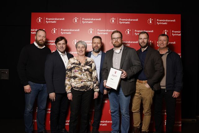 Hópur fólks situr fyrir á mynd fyrir framan rauðan vegg.