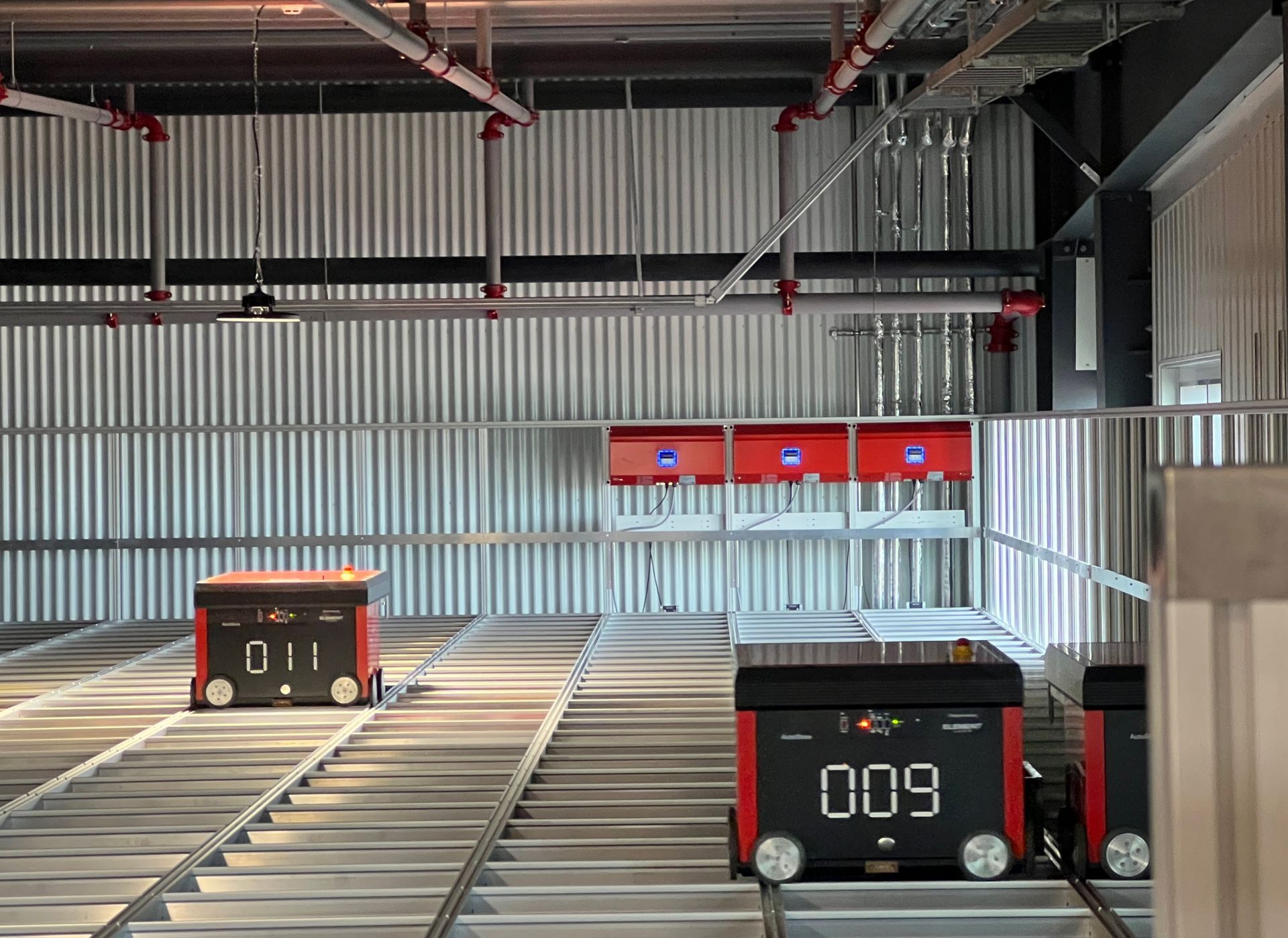 Two robots are sitting on a conveyor belt in a warehouse.