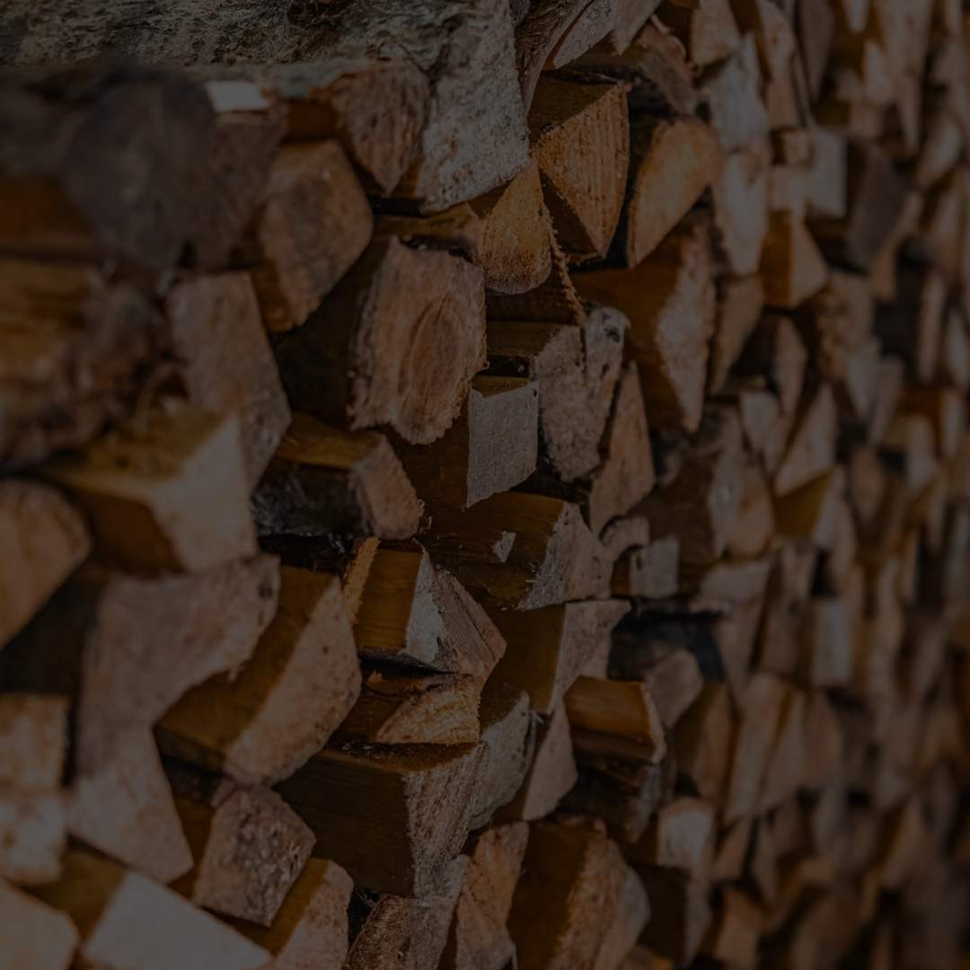 Firewood stacked and ready for processing beside a Firewood Processing Machine.