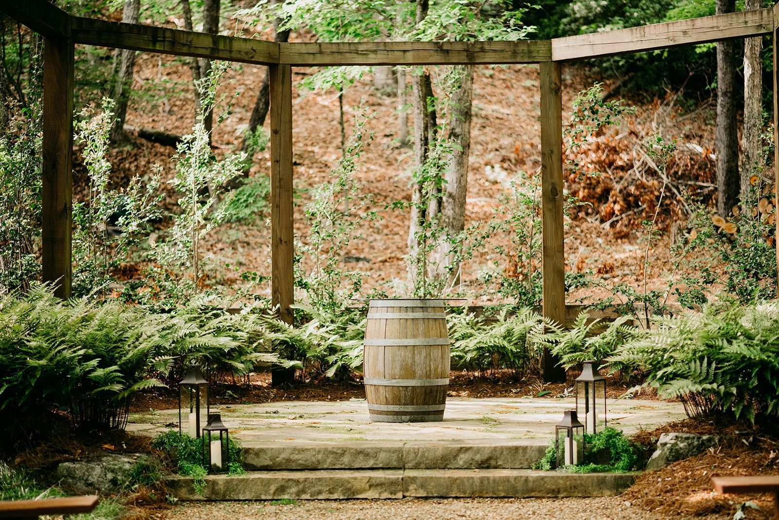 There is a wooden barrel in the middle of the woods.