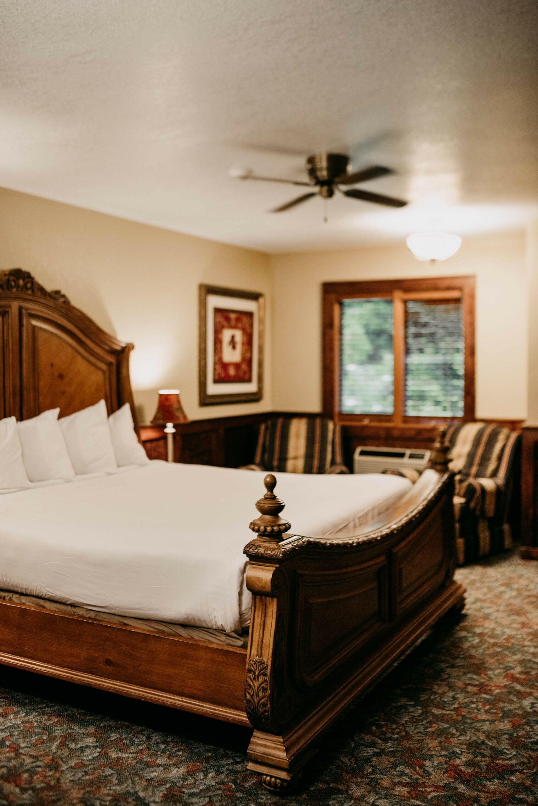A hotel room with a large bed and a ceiling fan.