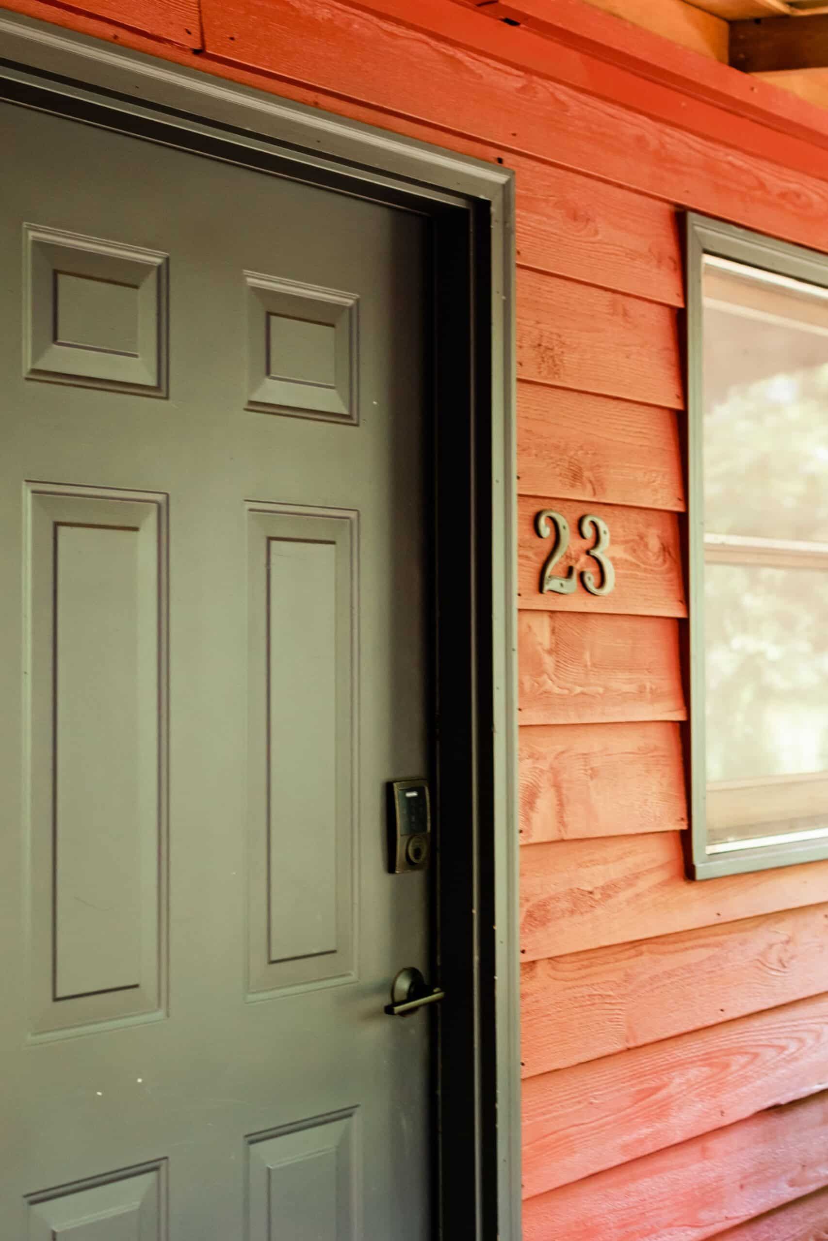 A door with the number 23 on it is on a wooden house.