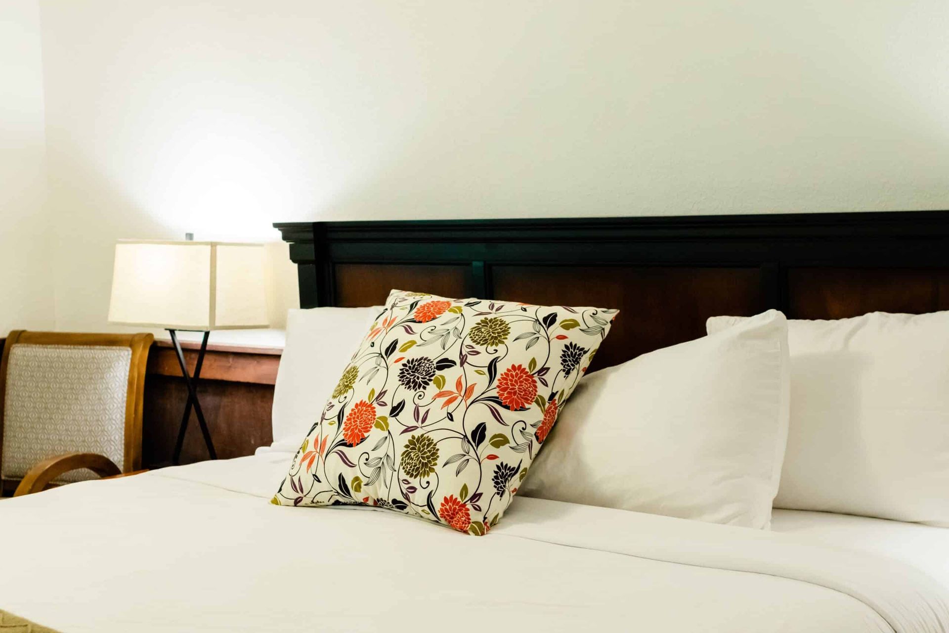 A bed with white sheets and a floral pillow on it