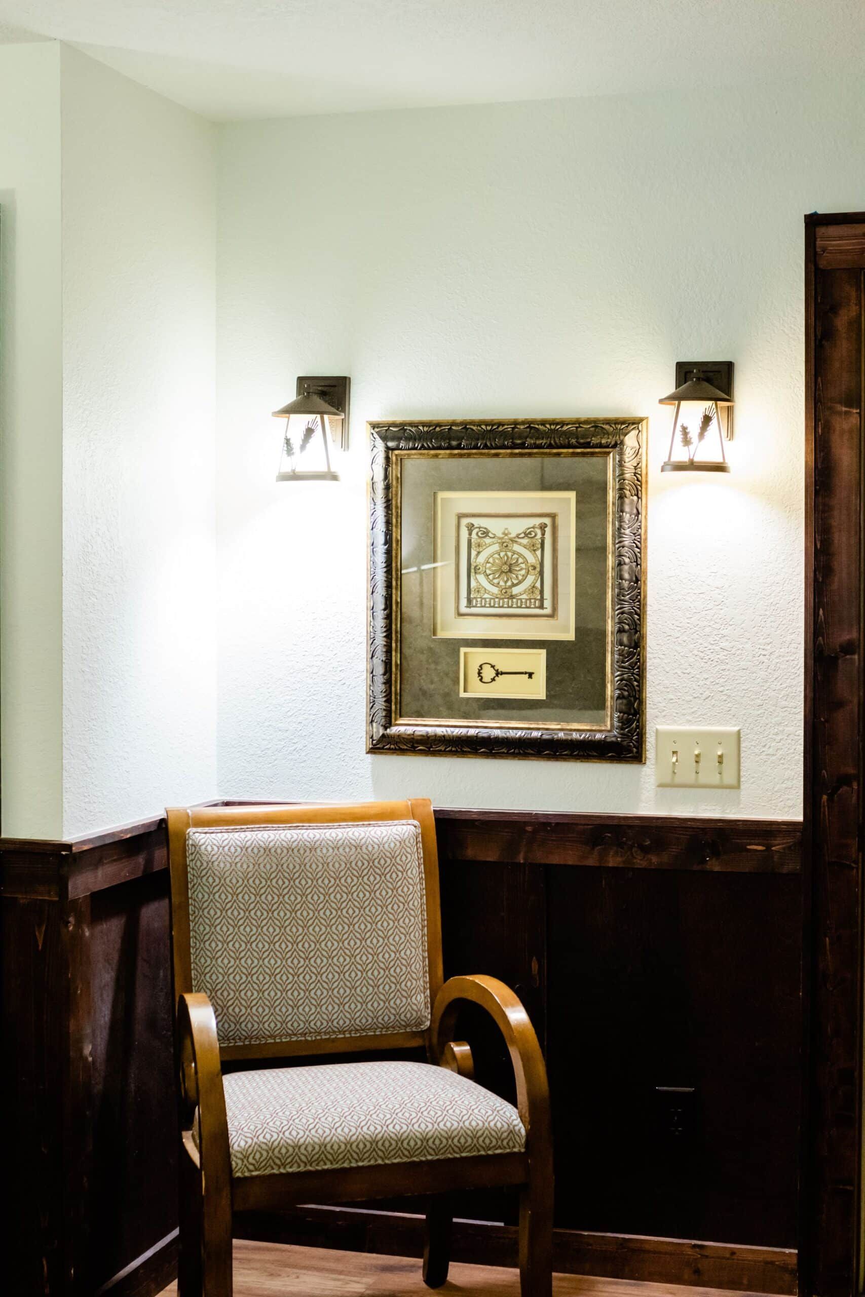 A chair is sitting in a hallway next to a picture on the wall.
