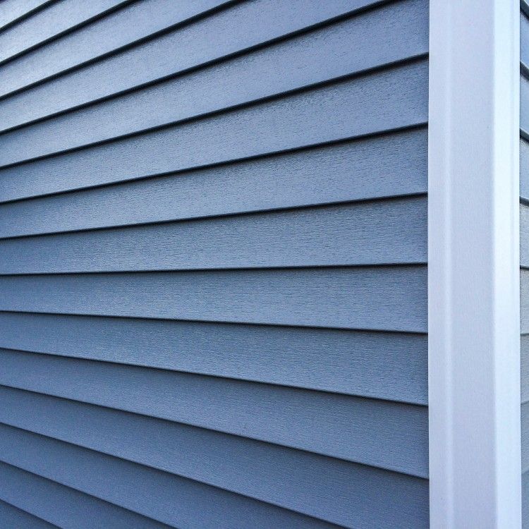 Blue-gray vinyl siding on a building exterior, viewed at an angle