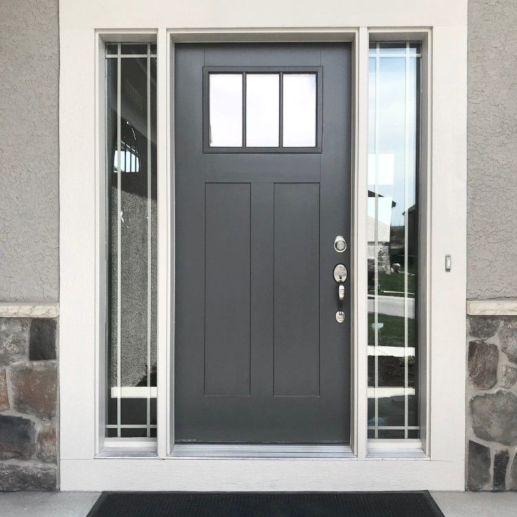 Gray front door with sidelights and small upper window in a stone and stucco entryway