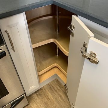 A kitchen with a corner cabinet with the door open