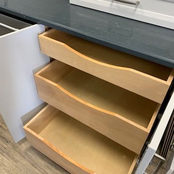 Three wooden drawers are open on a counter top.