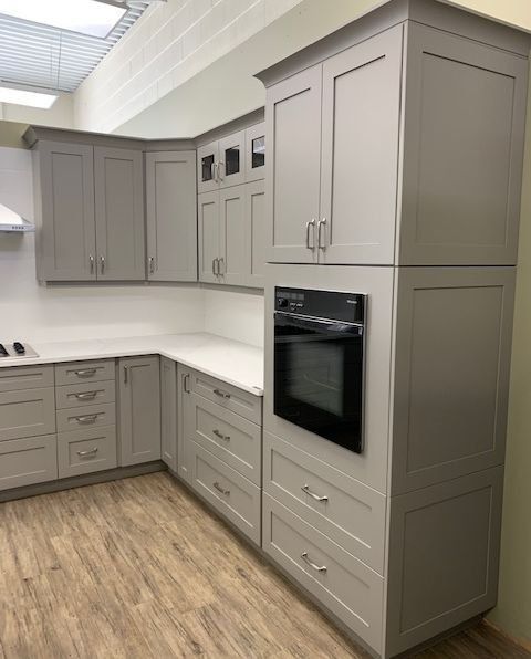 A kitchen with gray cabinets and a black oven.