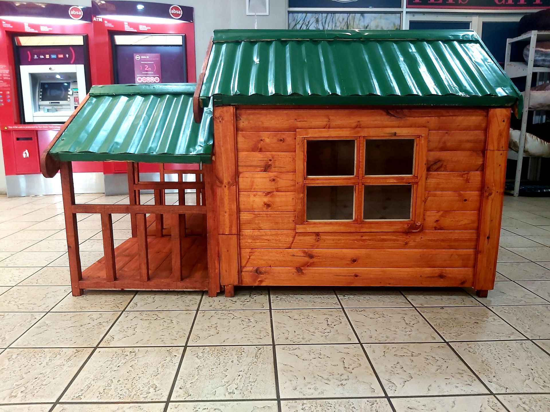 A small wooden dog house with a green roof from Pets and the City in Pretoria East.