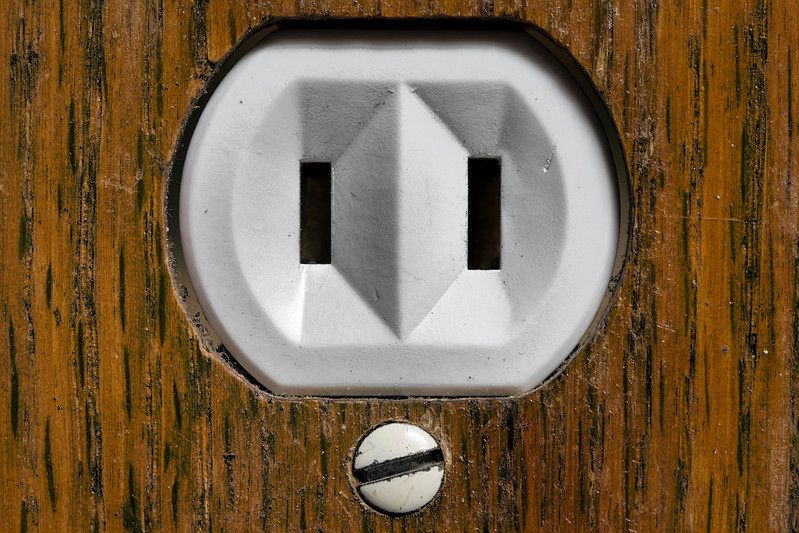 A close up of an electrical outlet on a wooden surface