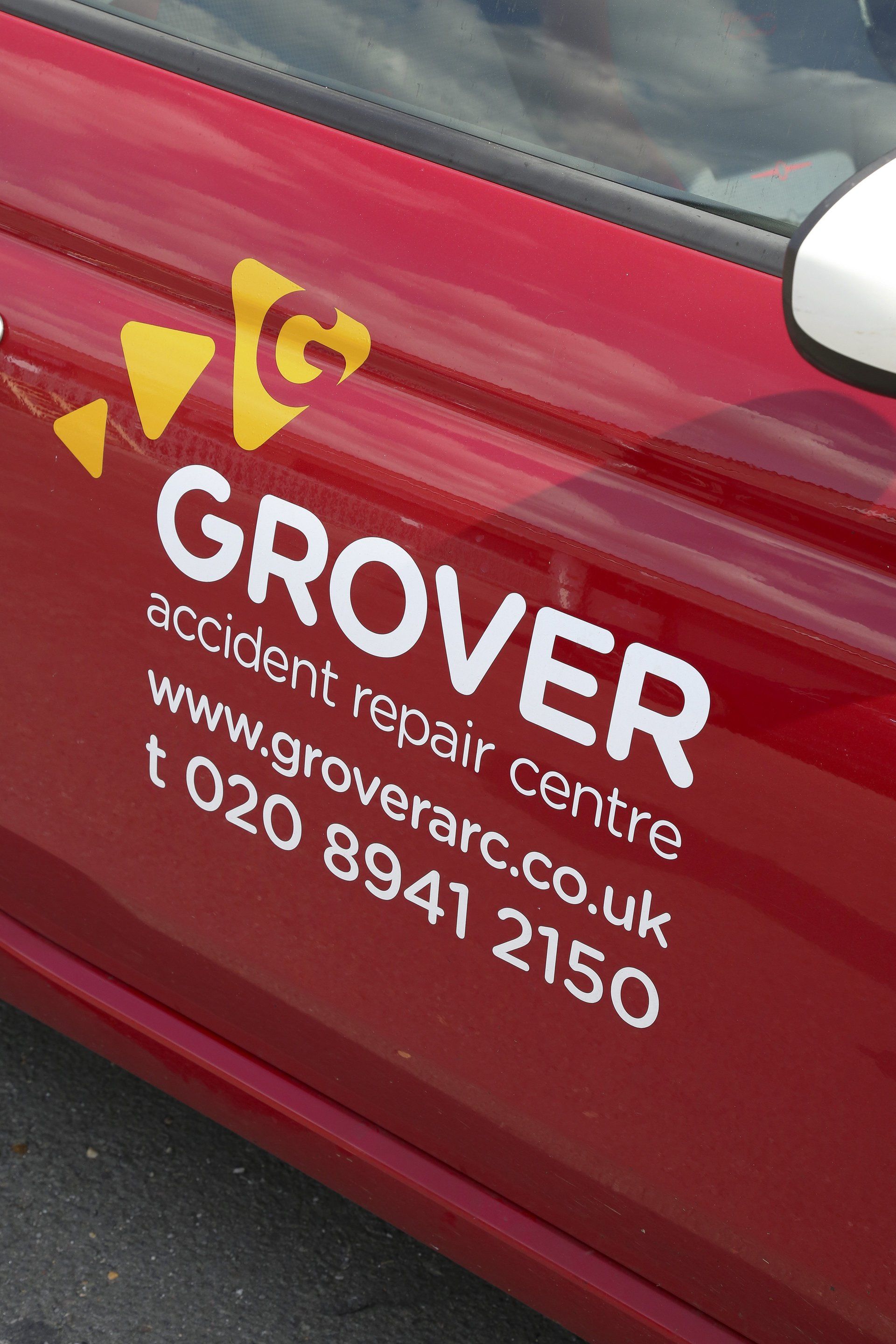 A red car with grover accident repair centre written on the side