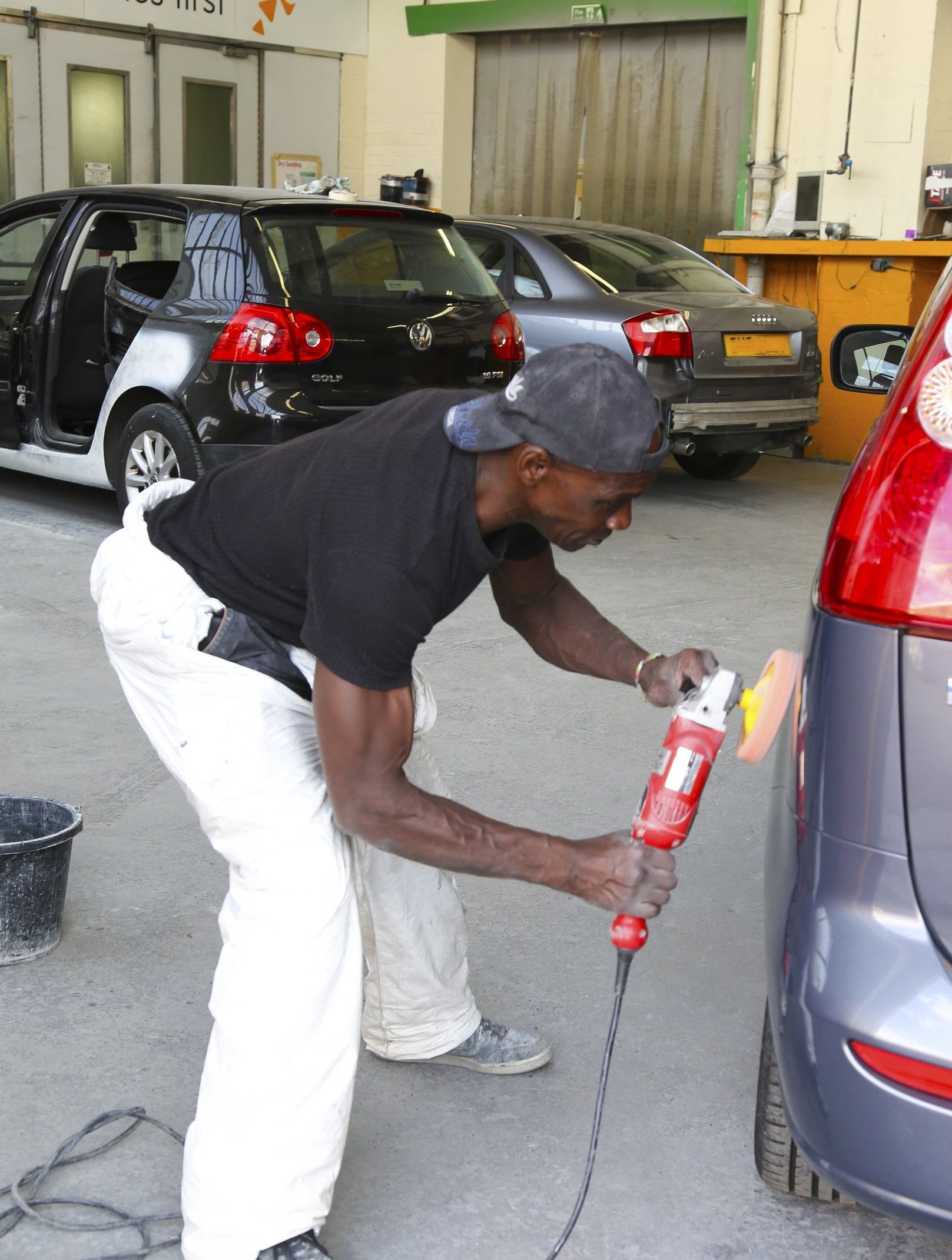 A man is polishing a car with a license plate that says ge
