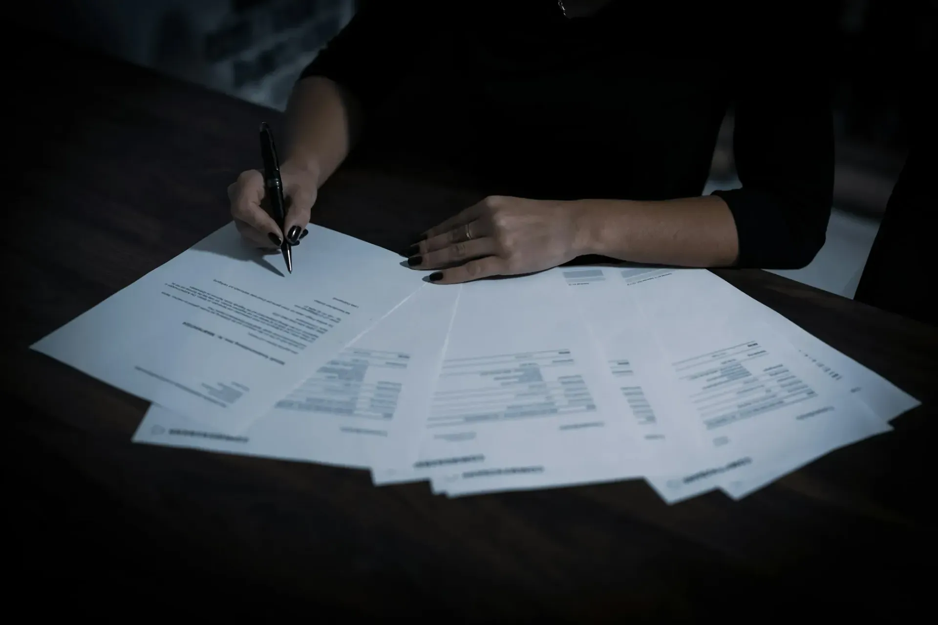 A woman is writing on a piece of paper with a pen