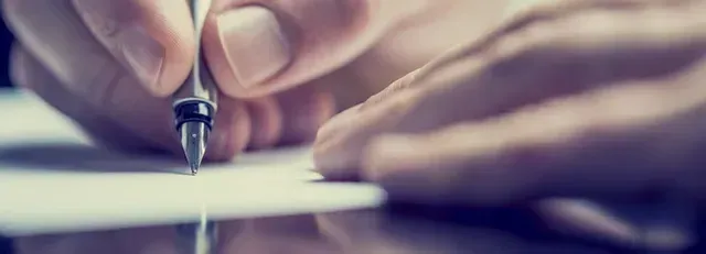 Close-up of hands writing with a pen on paper