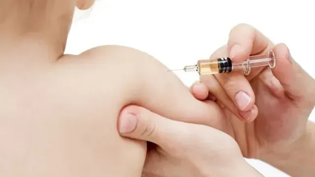 A person receives a shoulder injection with a syringe in a clinical setting.