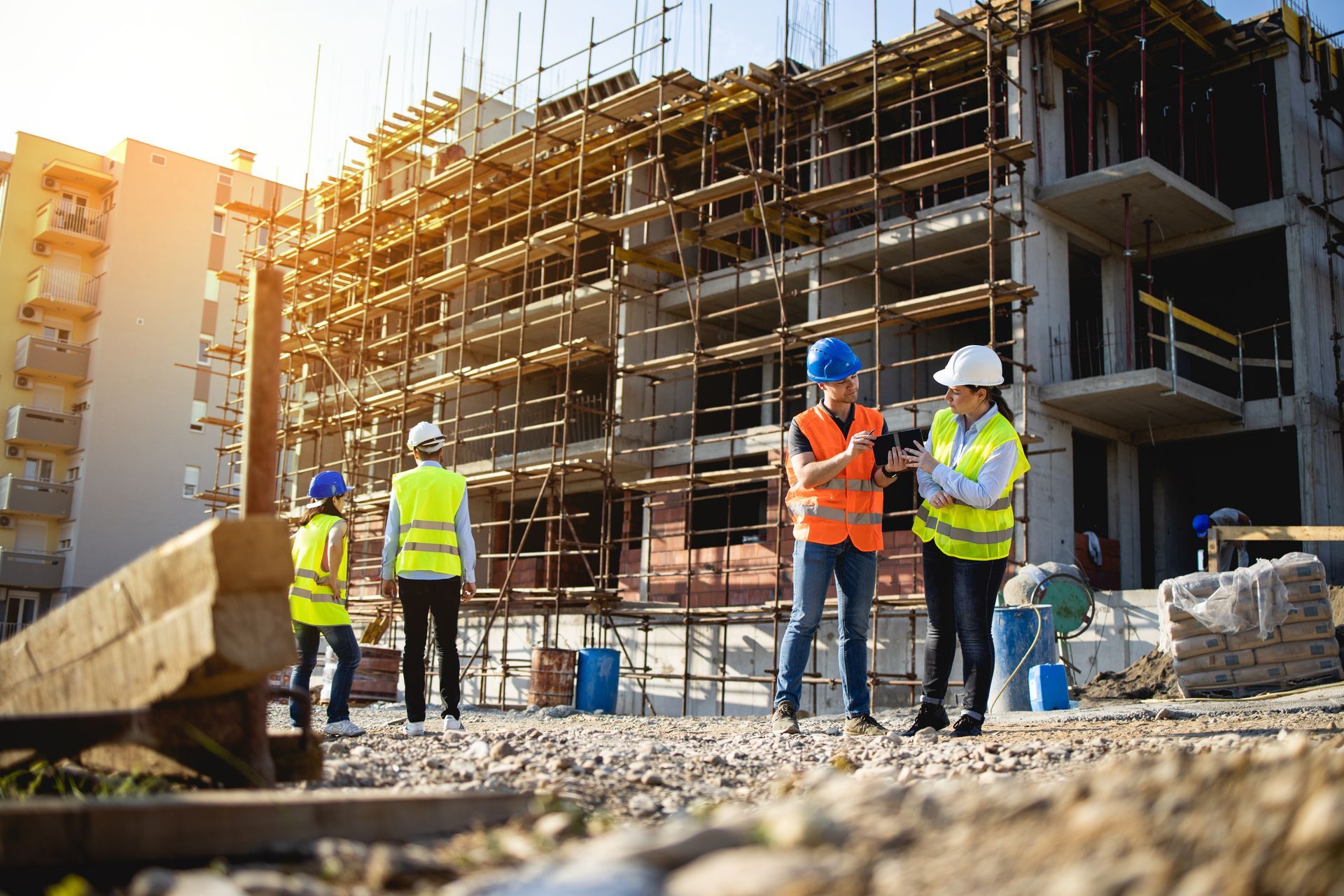 Construction workers at a building site, wearing safety vests and helmets. Sunlit setting. Construction workers at a building site, wearing safety vests and helmets. Sunlit setting.