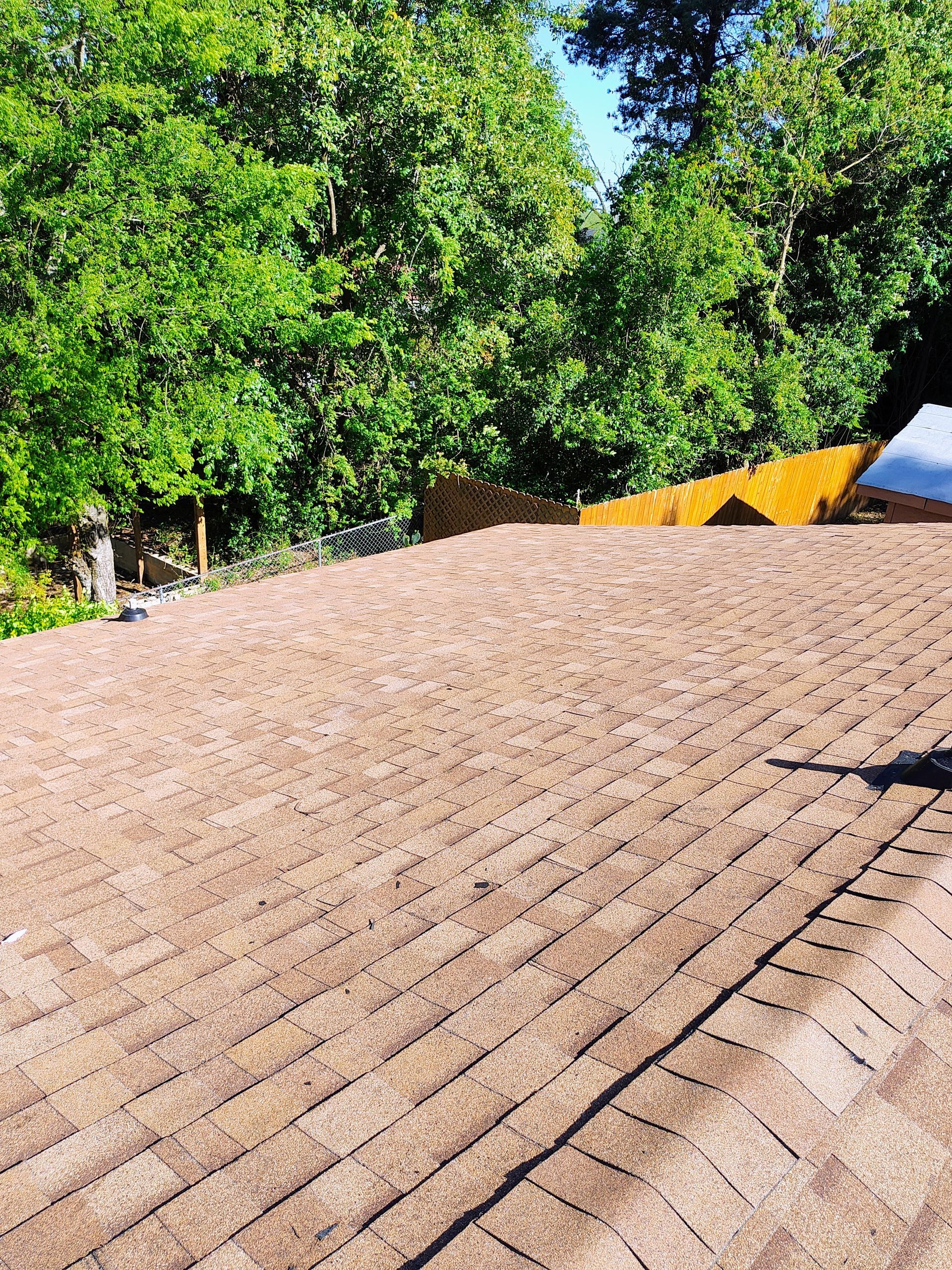 A roof with a lot of shingles and trees in the background.