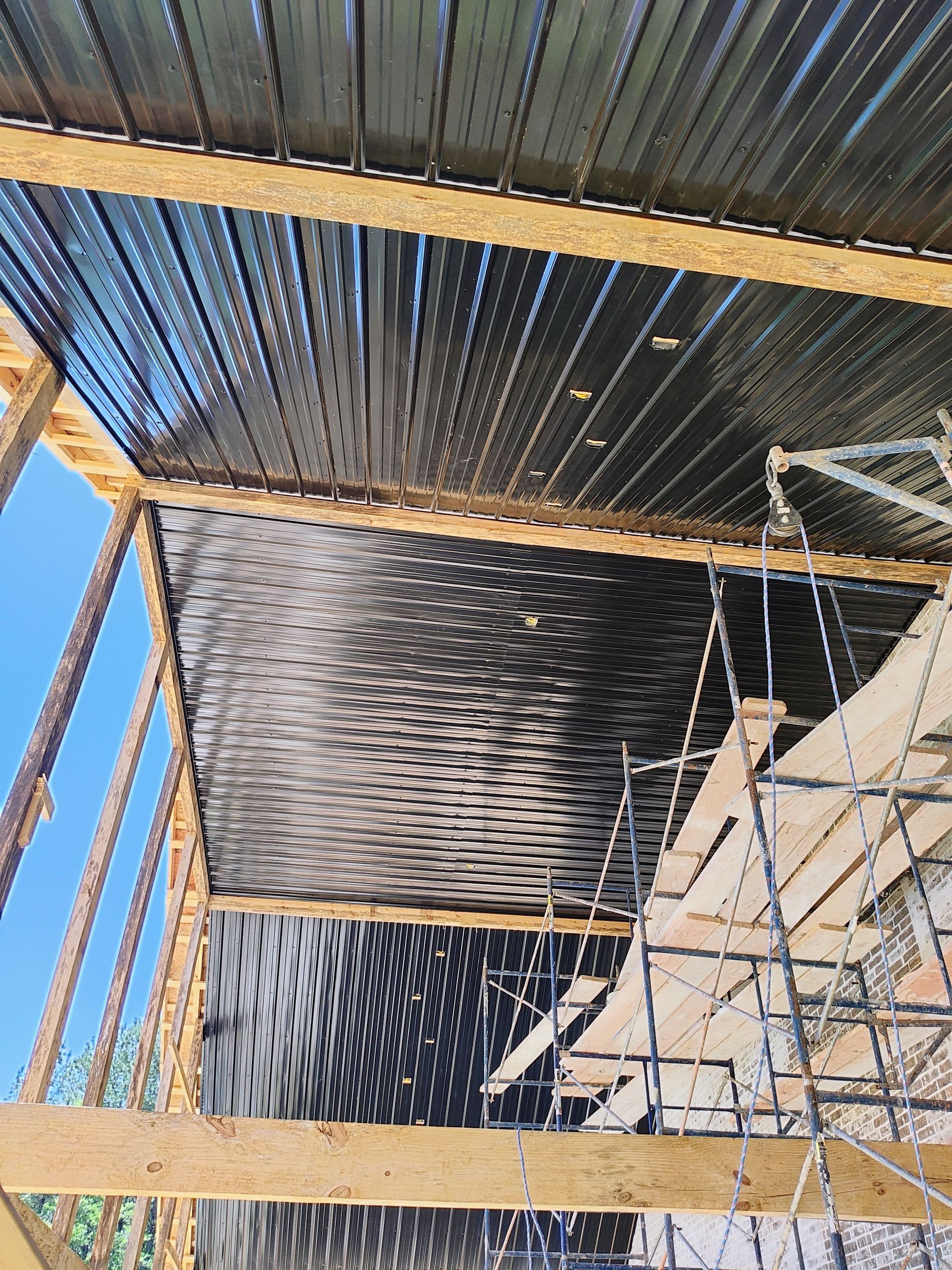 A building under construction with a wooden frame and a metal roof.