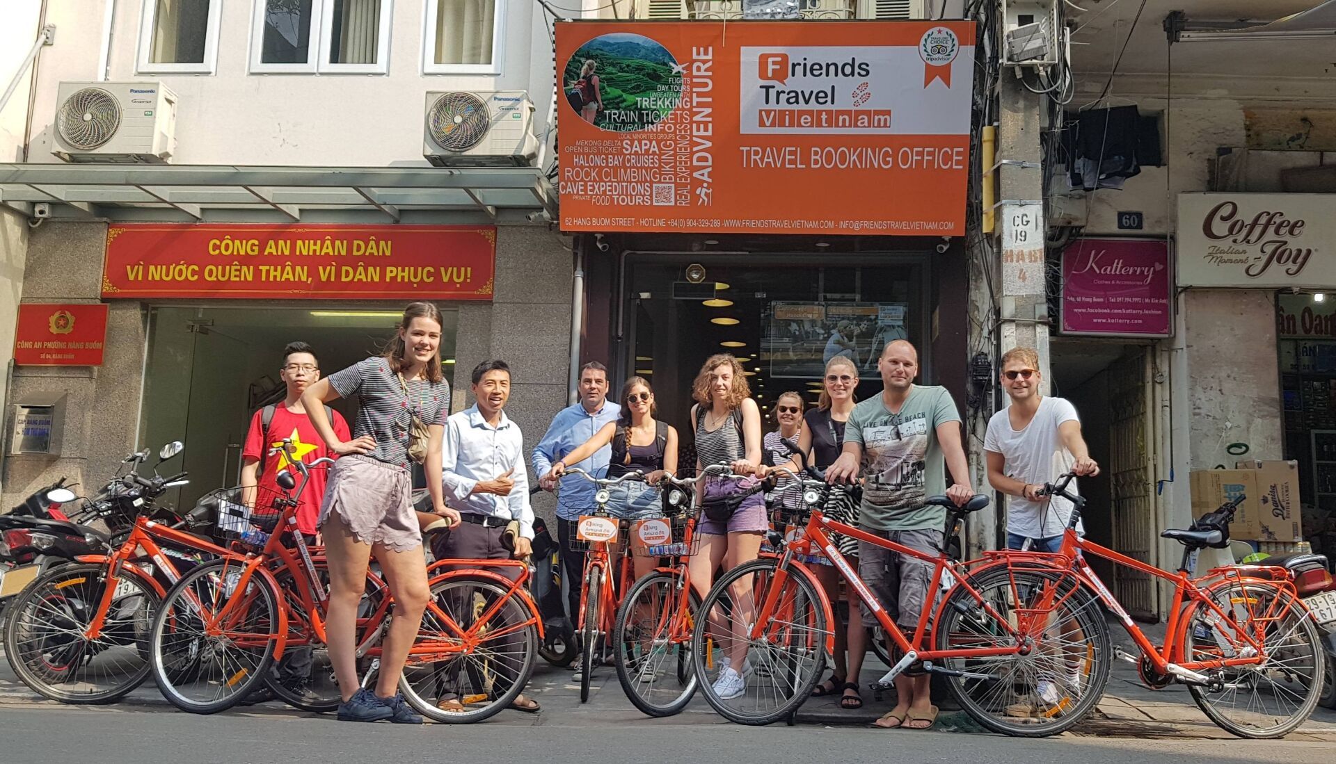 A group of people standing in front of a building with bicycles.