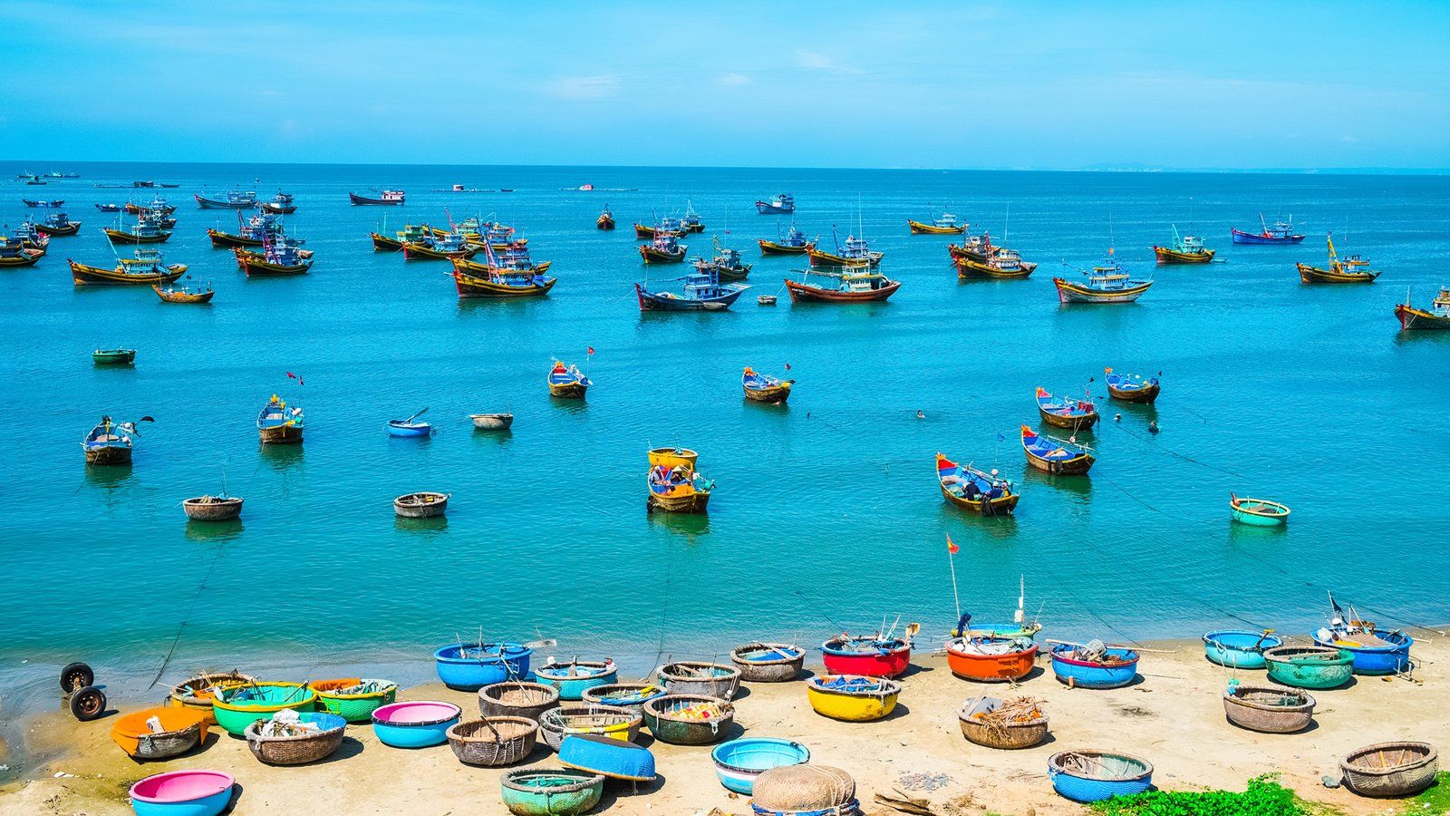 A beach filled with lots of colorful boats in the ocean.