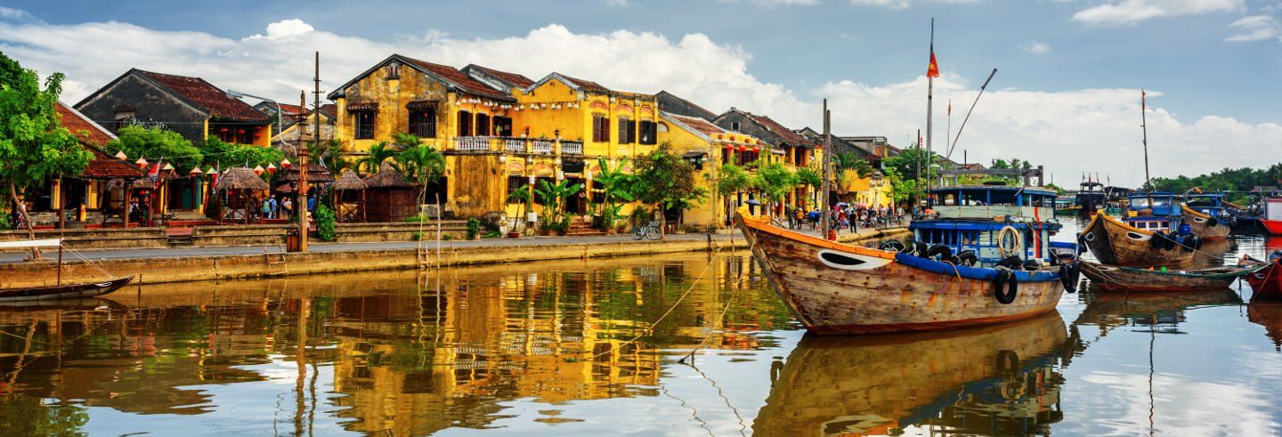 A boat is docked in front of a building next to a body of water.
