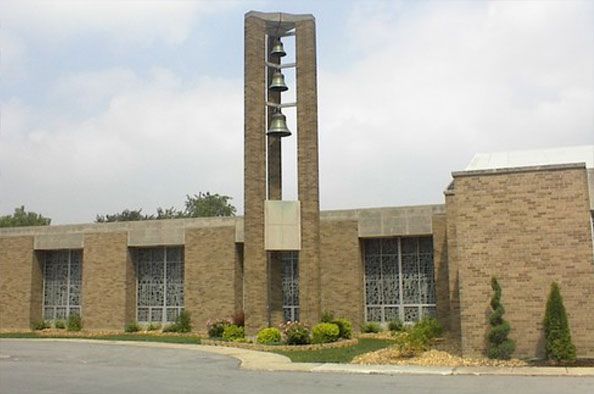 A large brick building with a bell tower in front of it