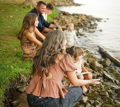 Family sitting on a rocky riverbank, watching the water together.