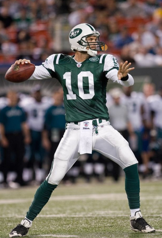 Football quarterback in green jersey #10 preparing to throw the ball on the field