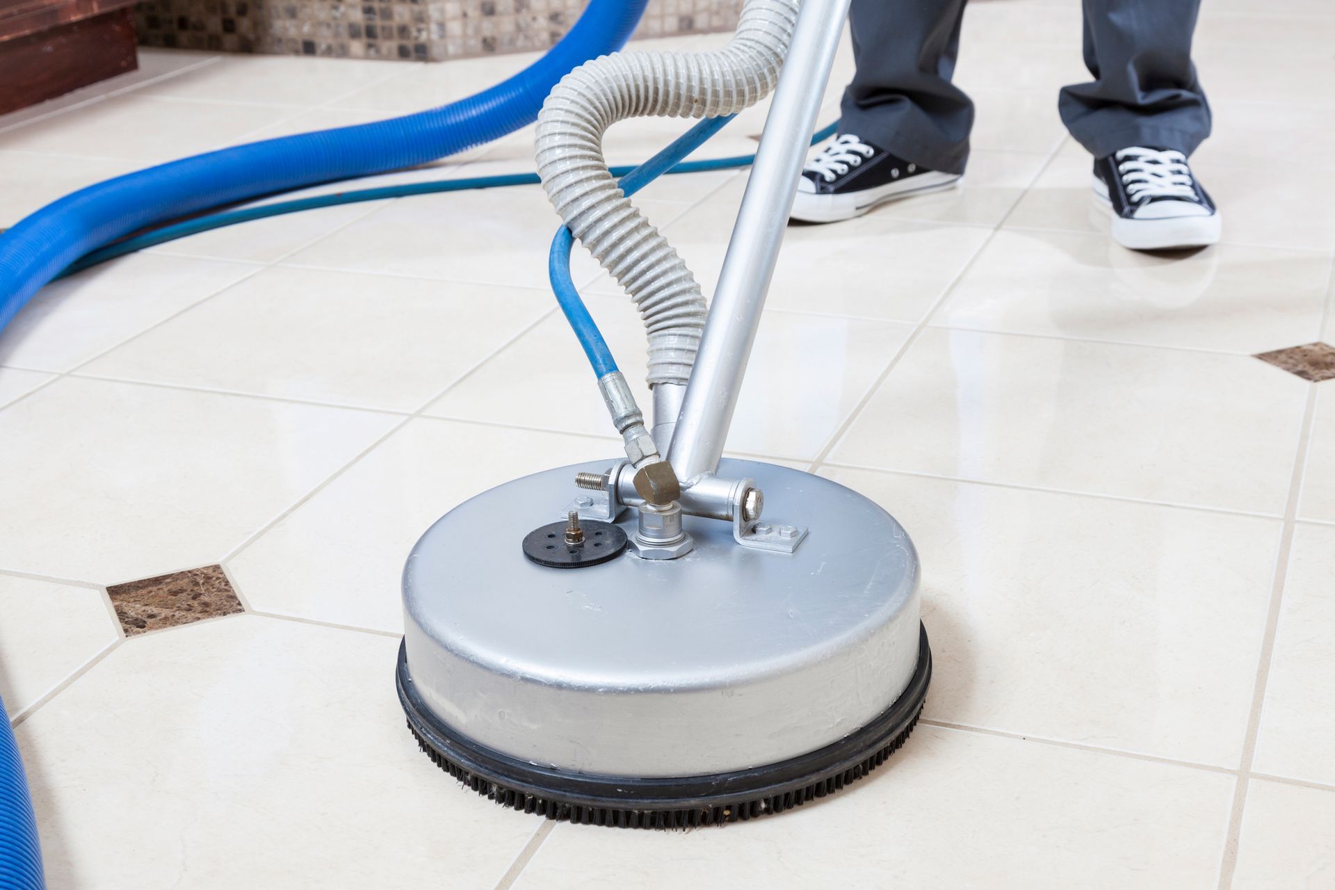 A person is cleaning a tile floor with a vacuum cleaner. A person is cleaning a tile floor with a vacuum cleaner.
