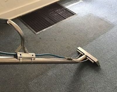 A person is using a vacuum cleaner to clean a rug in a living room. A person is using a vacuum cleaner to clean a rug in a living room.