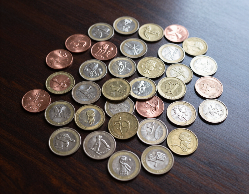 Mixed copper, silver, and gold coins spread on a dark wooden counter