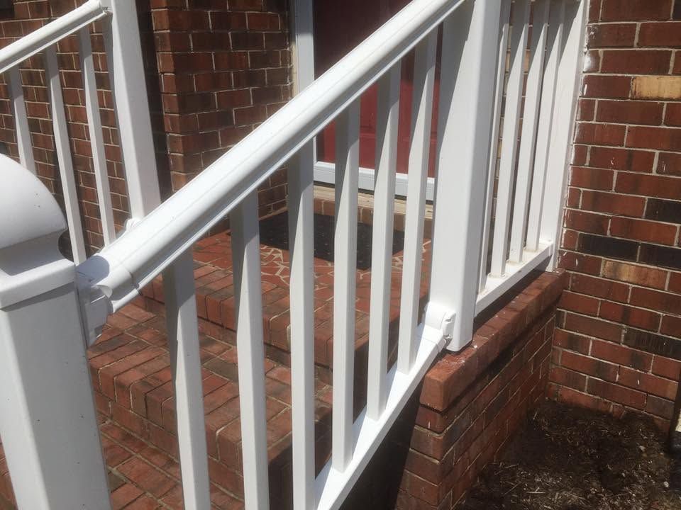 White porch railing with stairs beside a red brick house and brick steps