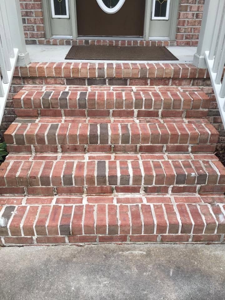 Brick front steps leading to a house entrance with a dark brown door and doormat