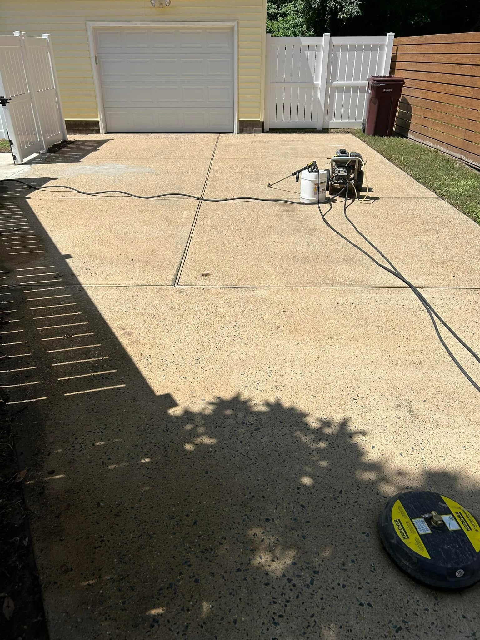 Driveway under construction with a wheelbarrow, hose, and garage in the background.