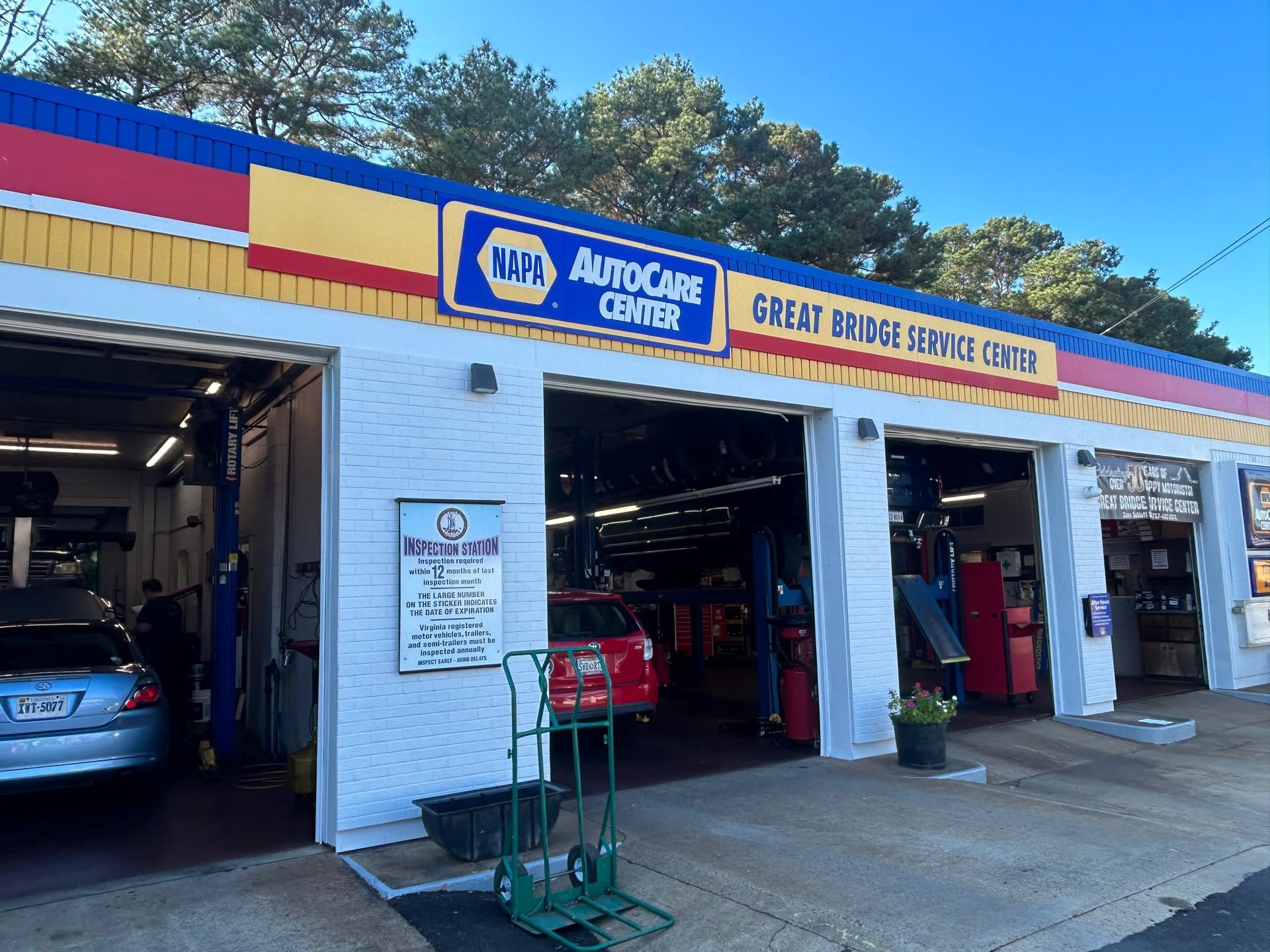 NAPA AutoCare service garage with open bays, cars inside, and a bright sign across the front