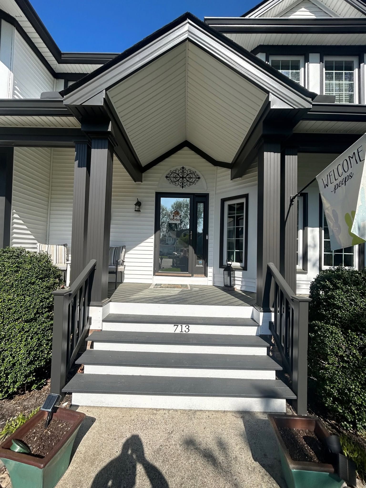 Front entrance of a house with white steps, black railings, and a covered doorway.